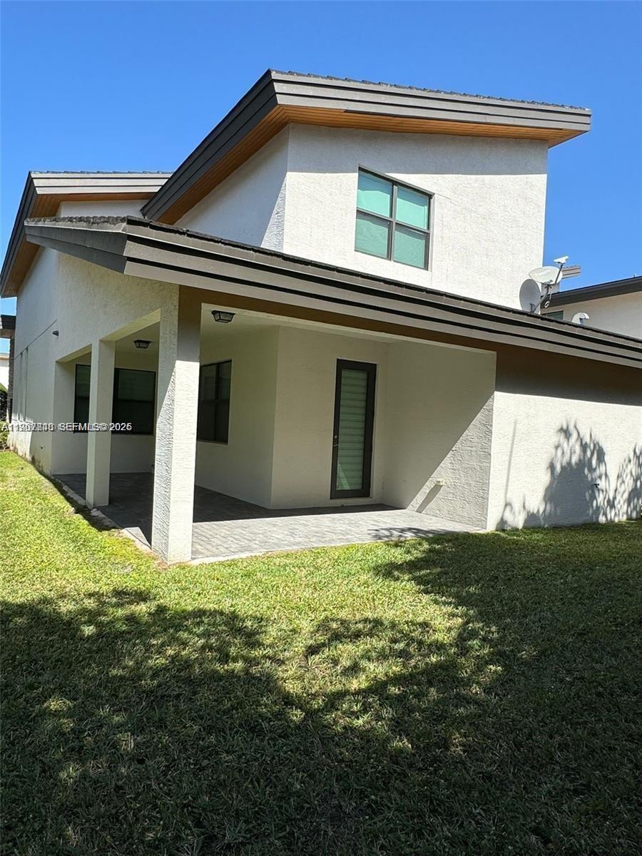 The exterior of a two-story house features a covered patio and a grassy backyard — 10376 NW 76th Ter, Doral FL 33178, DORAL, FL