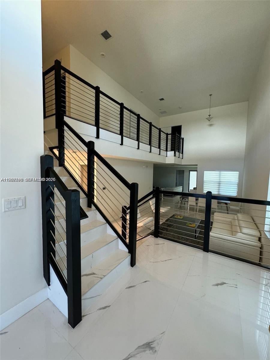 A staircase with black railings and white marble floors leads to an upper-level landing — 10376 NW 76th Ter, Doral FL 33178, DORAL, FL