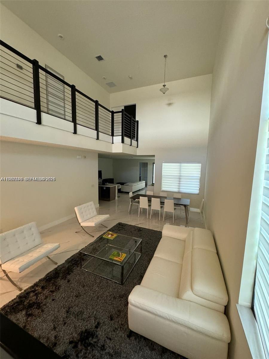 A high-ceilinged living and dining area features white furniture, a dark rug, and glass table — 10376 NW 76th Ter, Doral FL 33178, DORAL, FL