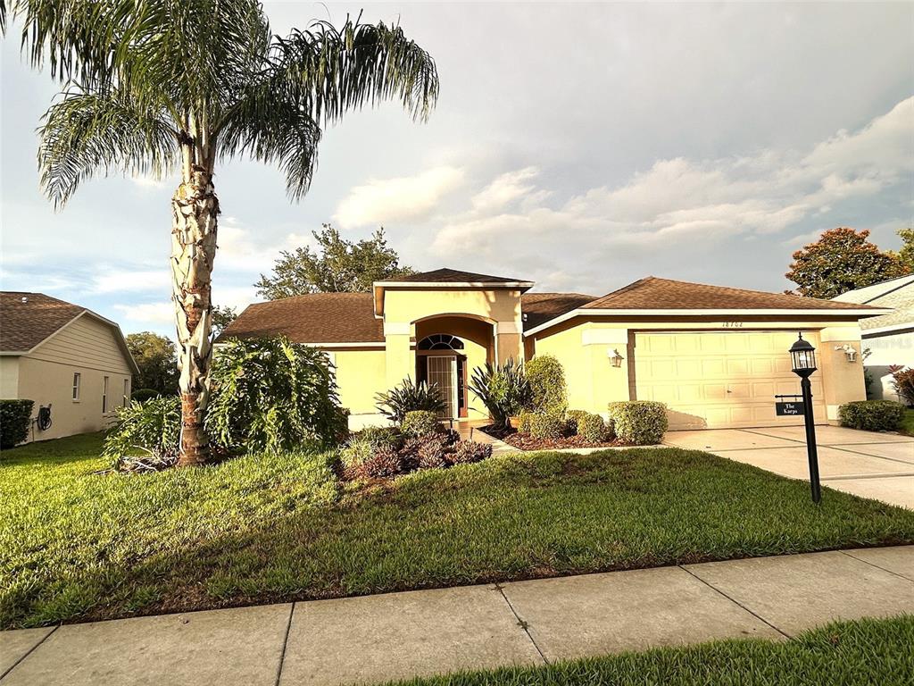 A single-story house with a palm tree, a two-car garage, and a landscaped front yard — 18702 BELLEVISTA COURT, HUDSON, FL