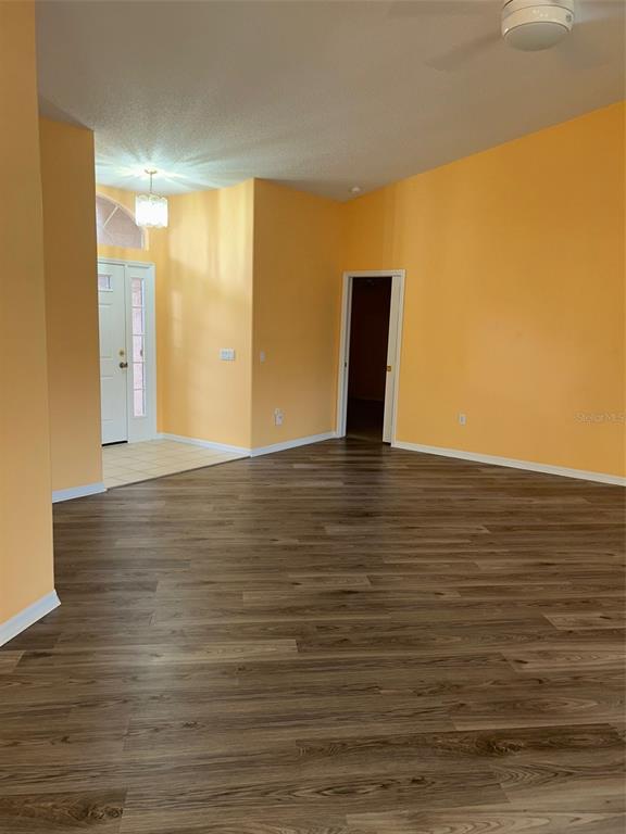 An interior view of a room with orange walls, wood-look flooring, and a white door — 18702 BELLEVISTA COURT, HUDSON, FL