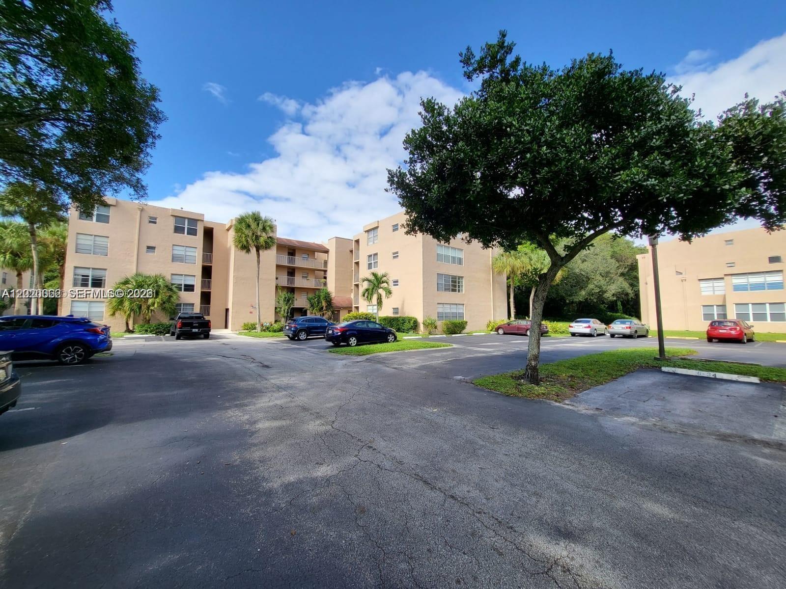 Exterior view of multi-story apartment buildings with a parking lot and trees — 9440 Live Oak Pl # 201, Davie FL 33324, DAVIE, FL