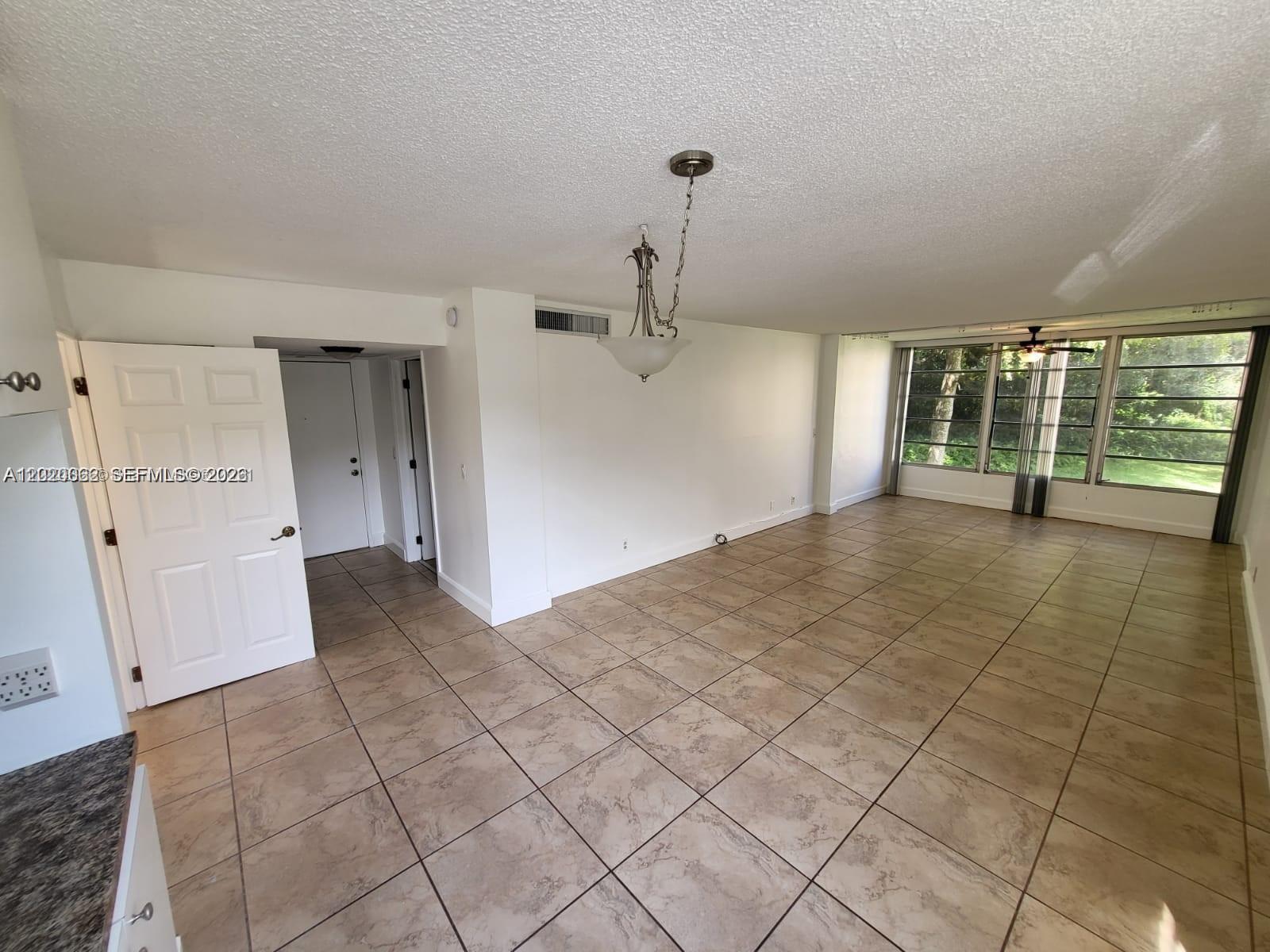 An open living area features beige tile flooring, white walls, and large windows — 9440 Live Oak Pl # 201, Davie FL 33324, DAVIE, FL