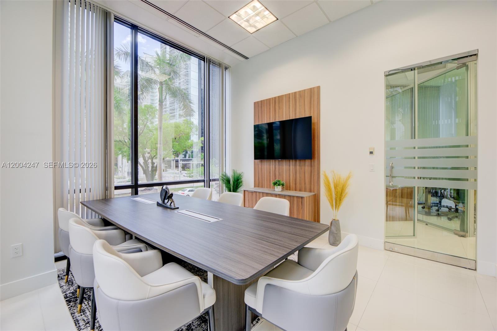 A modern conference room features a dark wood table, white chairs, and a wall-mounted television — 1200 Brickell Ave # K, Miami FL 33131, MIAMI, FL