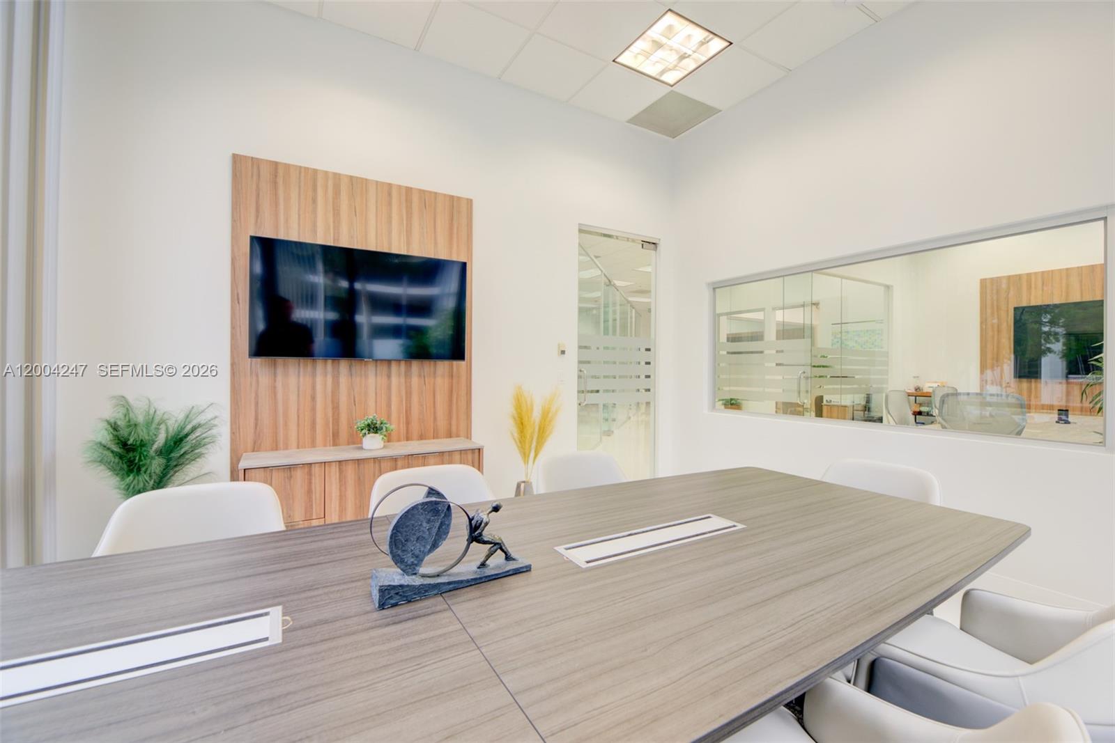 A modern conference room features a wood-paneled accent wall, a television, and a large table — 1200 Brickell Ave # K, Miami FL 33131, MIAMI, FL