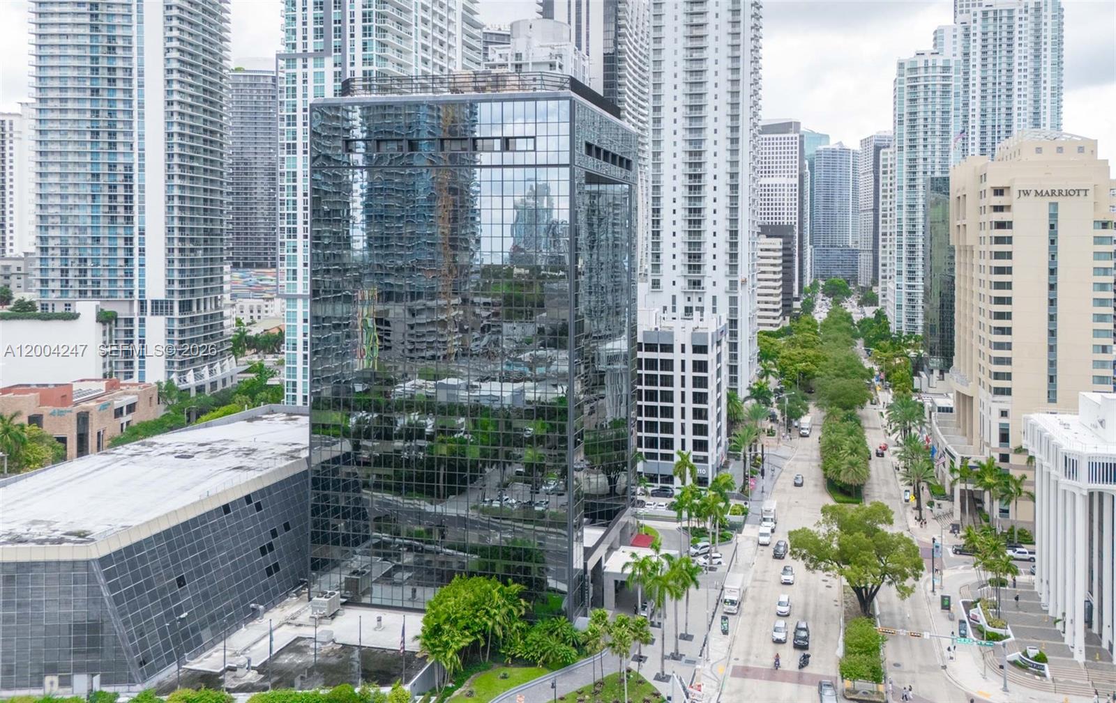 An aerial view shows a glass-clad office building surrounded by high-rise towers and city streets — 1200 Brickell Ave # K, Miami FL 33131, MIAMI, FL