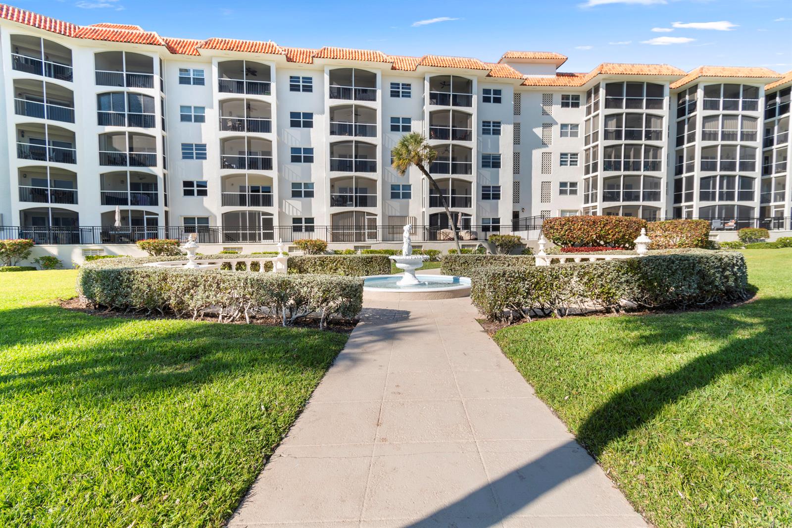 A paved walkway leads to a central fountain in front of a multi-story apartment building — 2871 N Ocean Boulevard # C123, Boca Raton FL 33431, BOCA RATON, FL
