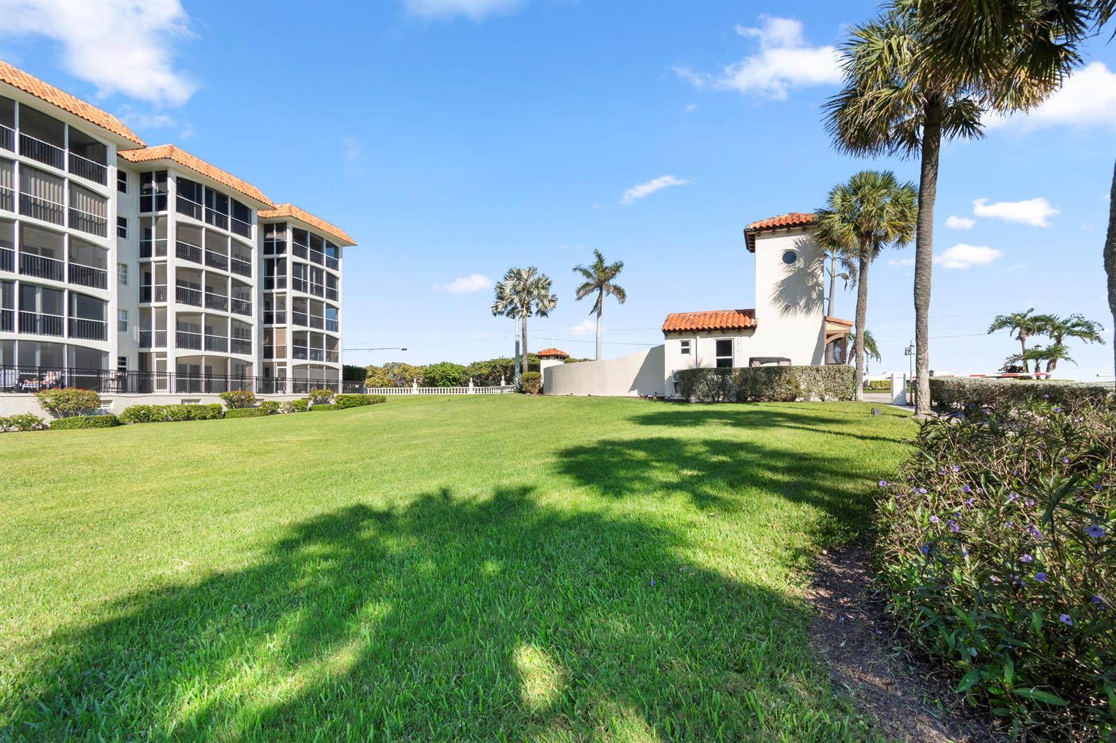 A large grassy lawn sits between a multi-story apartment building and a small gatehouse — 2871 N Ocean Boulevard # C123, Boca Raton FL 33431, BOCA RATON, FL