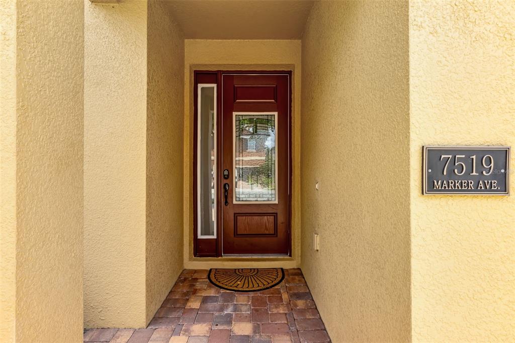 A front entryway features a dark wood door with a glass insert and a stone floor — 7519 MARKER AVENUE, KISSIMMEE, FL
