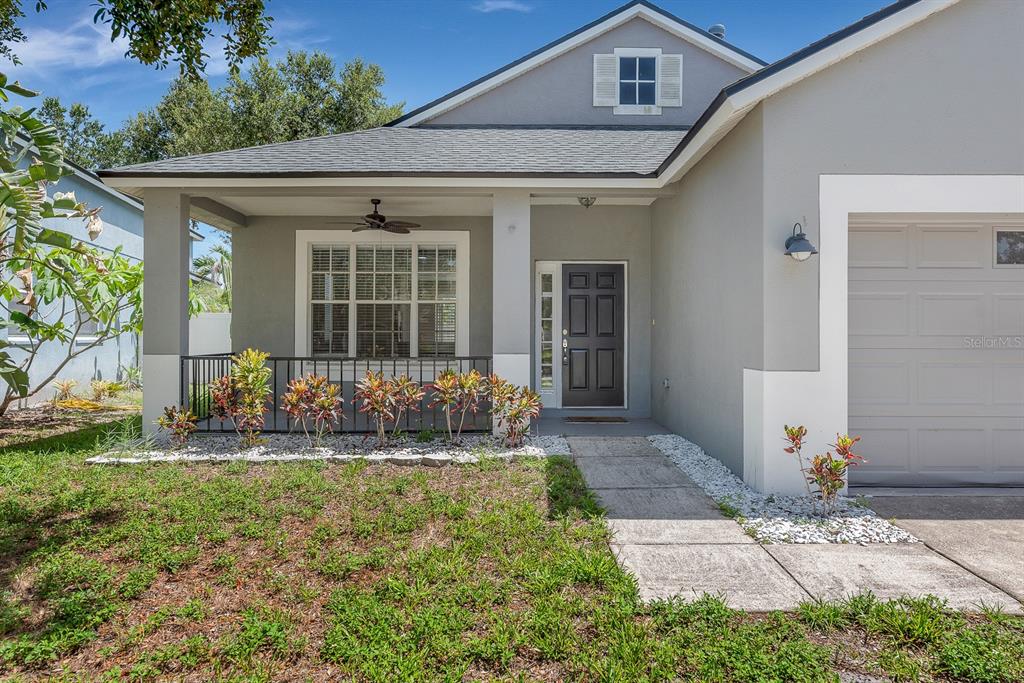 A gray house with a front porch, a dark front door, and a garage — 12737 BRAMFIELD DRIVE, RIVERVIEW, FL
