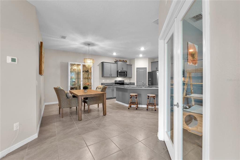A kitchen with gray cabinets and an island sits next to a dining area — 32313 LEXINGTON STREET, WESLEY CHAPEL, FL