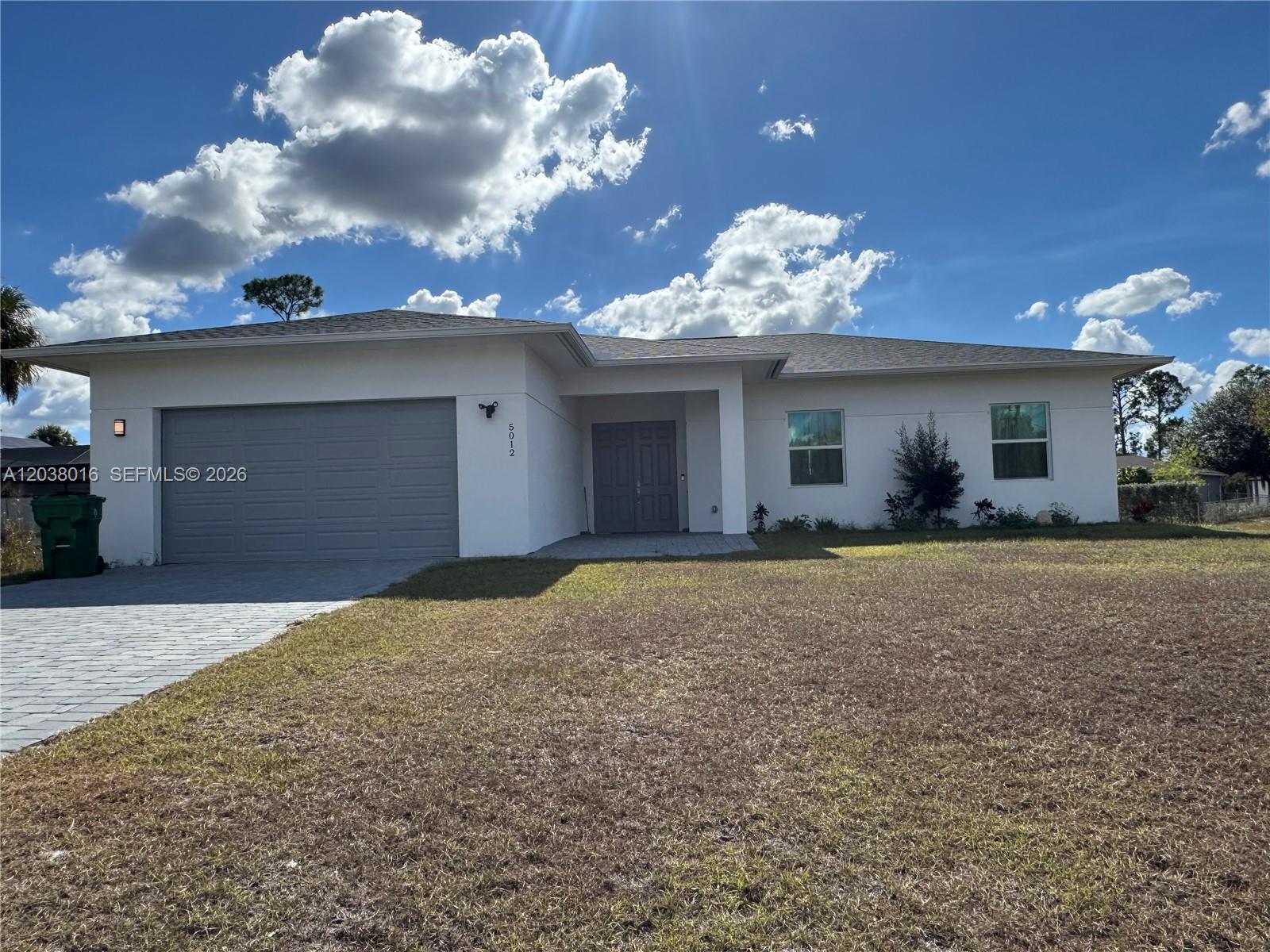 A single-story white house with a gray garage door and a paved driveway — 5012 Gunn PL # 0, La Belle FL 33935, LA BELLE, FL