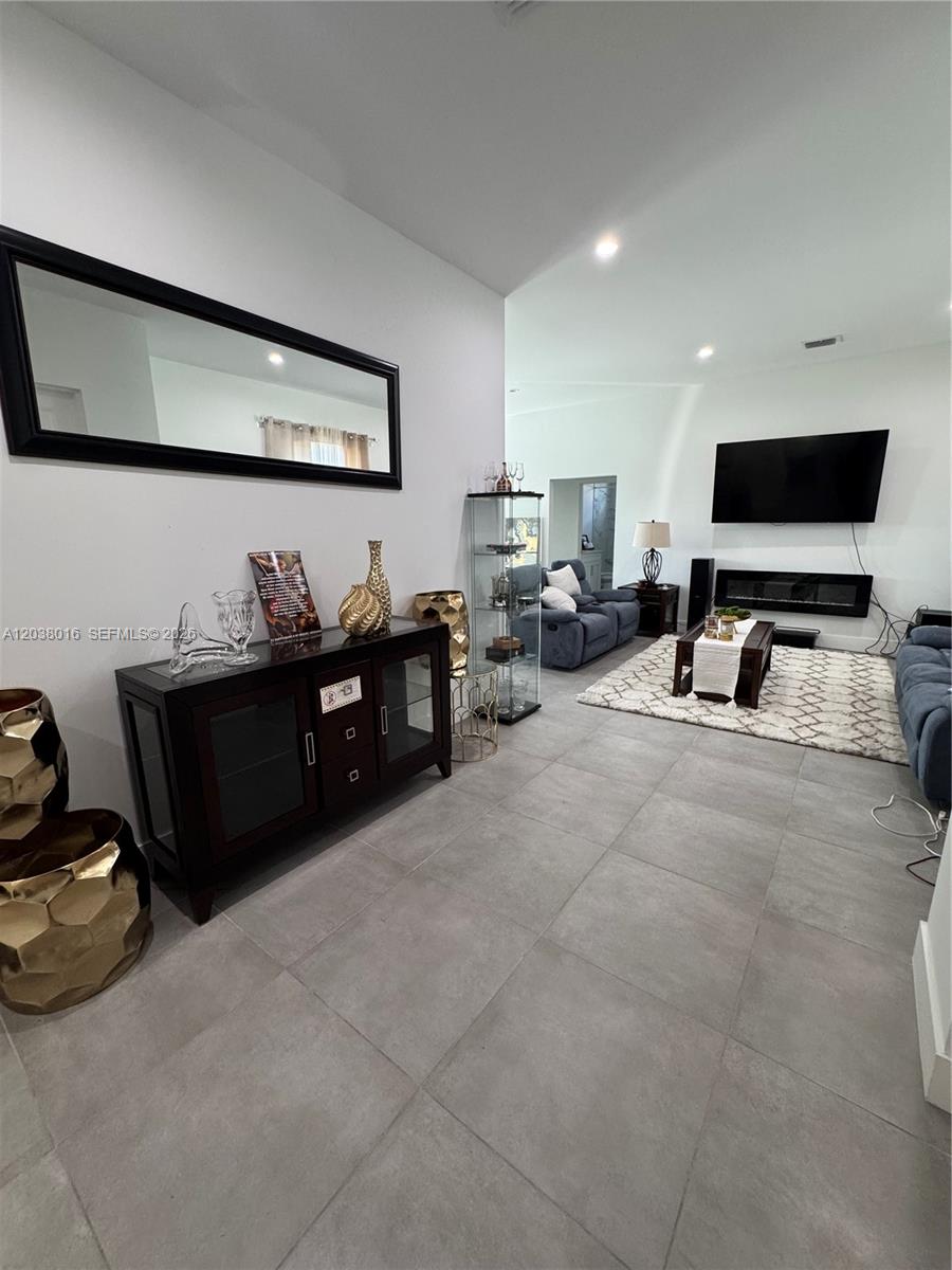 A living room features large gray floor tiles, a dark console table, and a fireplace — 5012 Gunn PL # 0, La Belle FL 33935, LA BELLE, FL