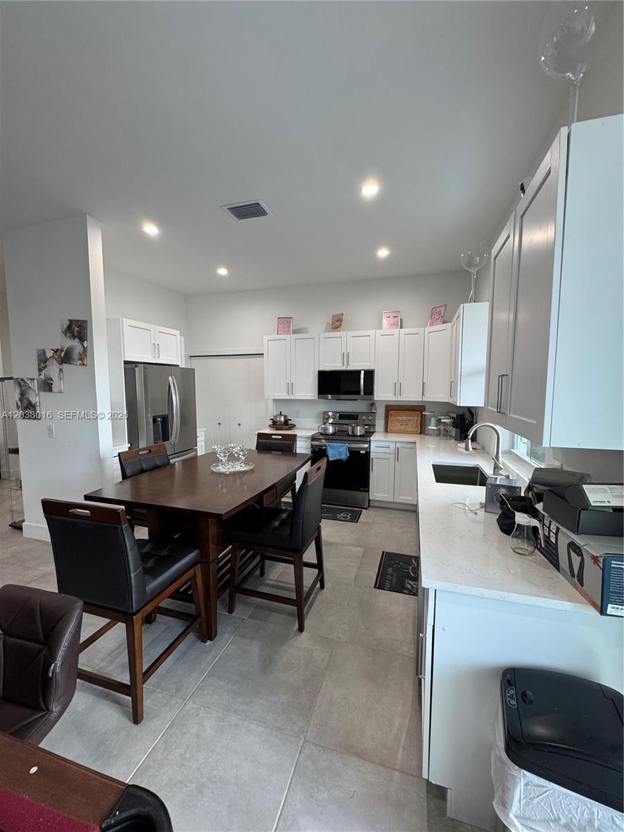 A kitchen features white cabinets, stainless steel appliances, a dark wood dining table, and tile flooring — 5012 Gunn PL # 0, La Belle FL 33935, LA BELLE, FL