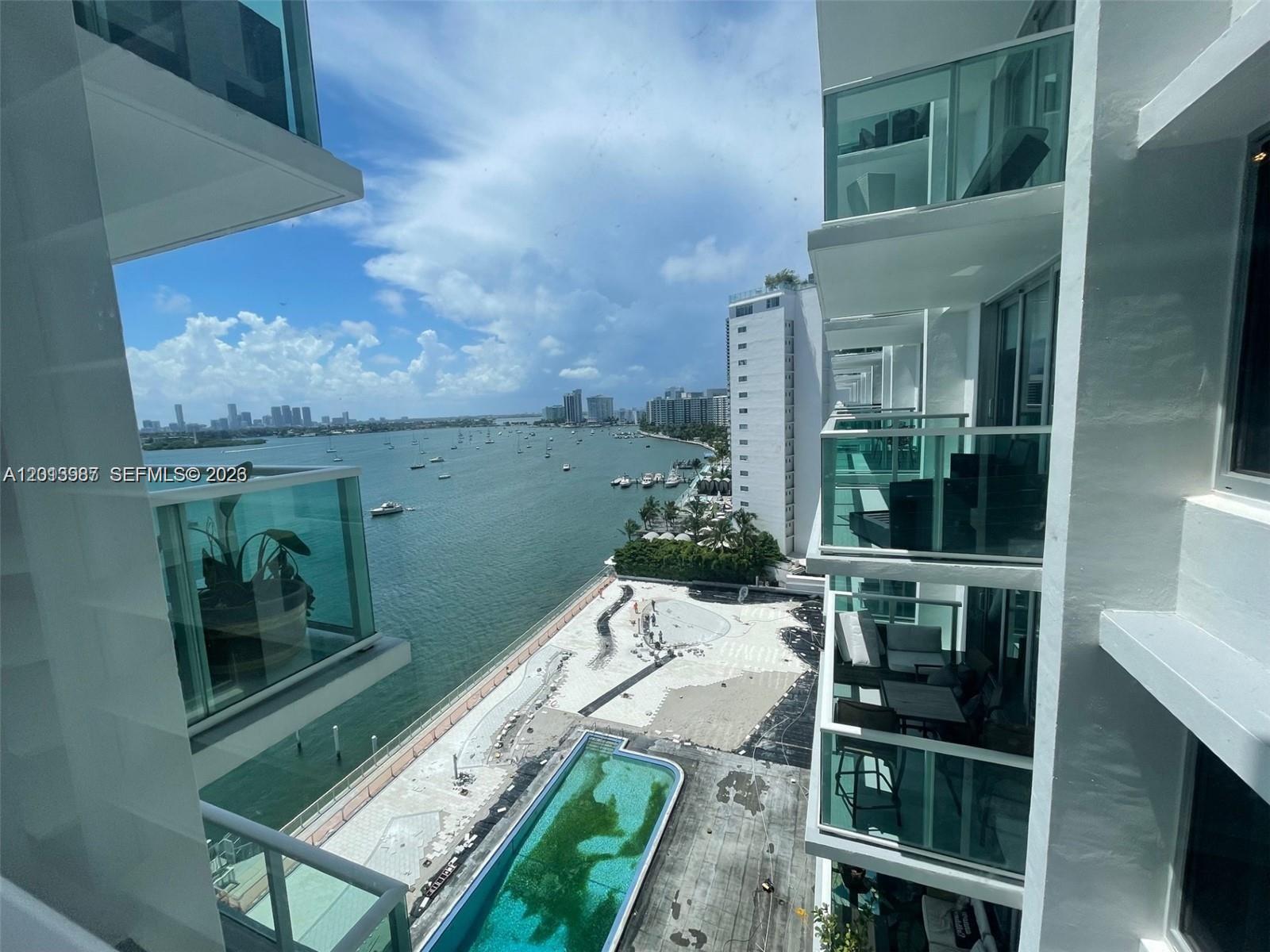 A high-angle view shows a waterfront swimming pool and balcony views of a bay — 1000 West Ave # 1122, Miami Beach FL 33139, MIAMI BEACH, FL