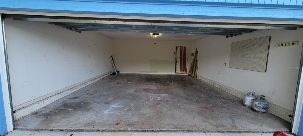 An empty two-car garage with a concrete floor, white walls, and a pegboard on the wall — 1425 NE OLD MILL DRIVE, DELTONA, FL