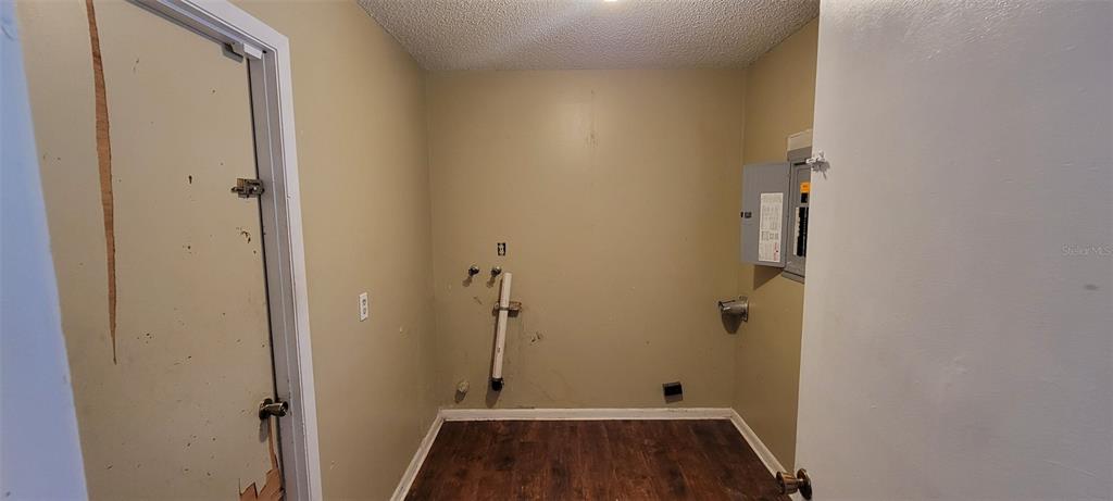 A laundry room features wood-look flooring, a utility sink hookup, and an exposed electrical panel — 1425 NE OLD MILL DRIVE, DELTONA, FL