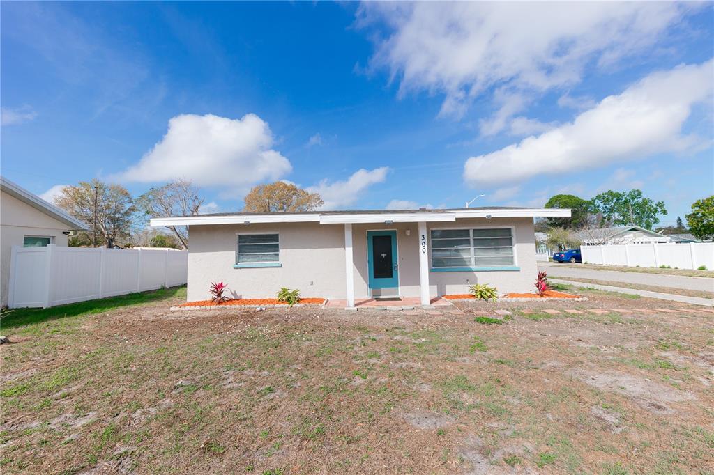 A single-story house with a light-colored exterior, a teal front door, and a large yard — 300 53RD STREET W, BRADENTON, FL