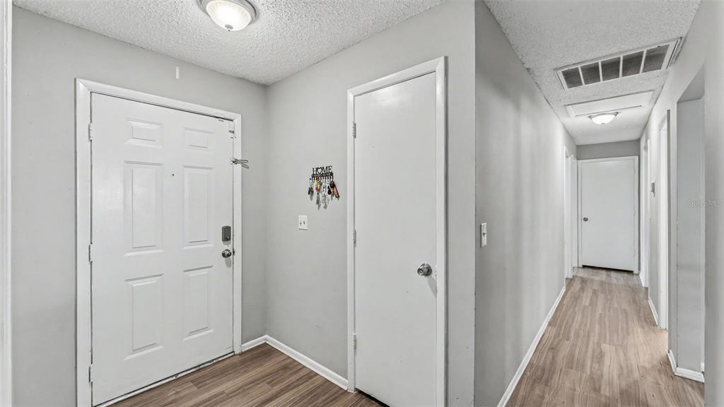 An entryway with a white door, a closet, and a hallway with wood-look flooring — 1309 CINNAMON WAY W, LAKELAND, FL