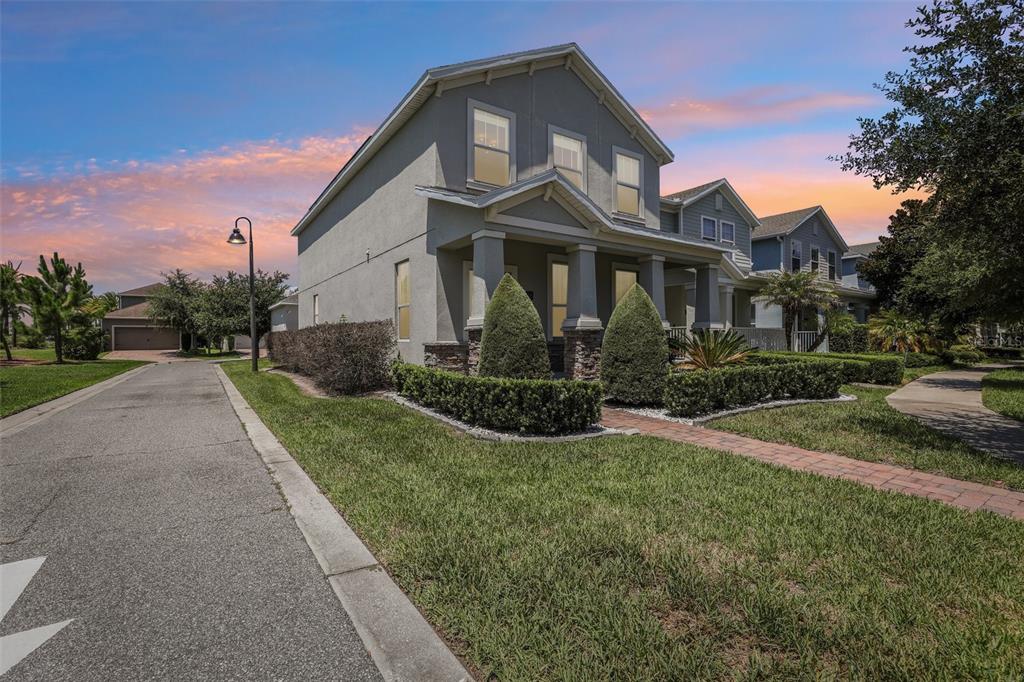 A two-story gray house with a front porch and stone accents sits along a street — 11886 FICTION AVENUE, ORLANDO, FL