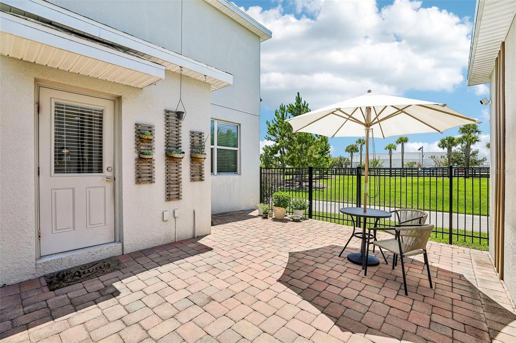 A paved patio features a small table with two chairs under an umbrella by a fence — 11886 FICTION AVENUE, ORLANDO, FL