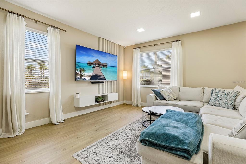 A living room features a wall-mounted television, a floating console, and a sectional sofa — 11886 FICTION AVENUE, ORLANDO, FL
