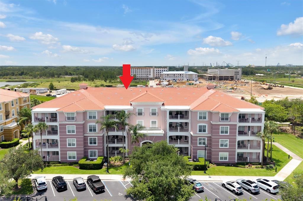 An aerial view of a multi-story pink apartment building with a red tile roof — 5048 SHOREWAY LOOP UNIT 10204, ORLANDO, FL