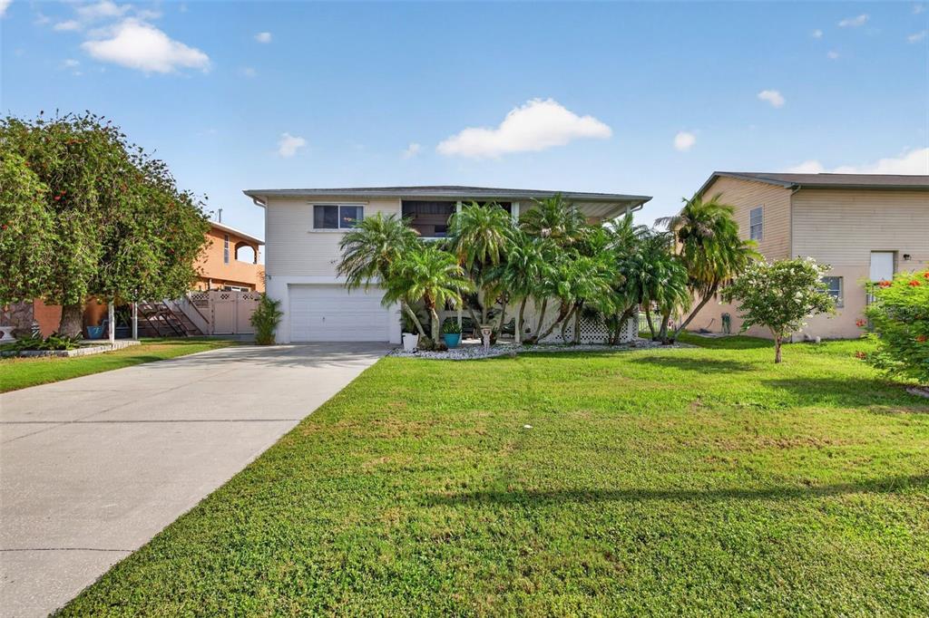 A two-story house with a white garage, palm trees, and a large front lawn — 7611 MAKO DRIVE, HUDSON, FL