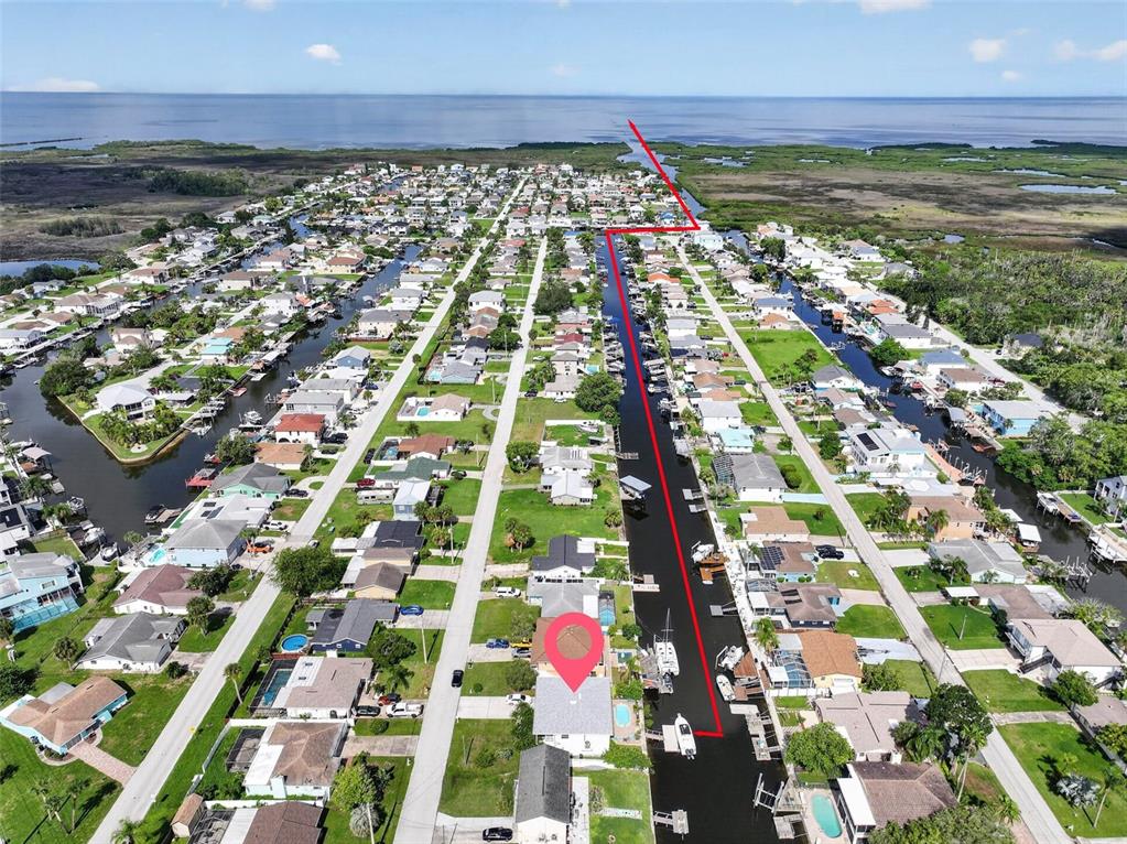 An aerial view shows a waterfront residential neighborhood with a red line highlighting a canal — 7611 MAKO DRIVE, HUDSON, FL