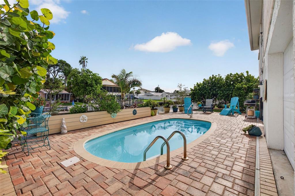 A backyard features a swimming pool, brick paver patio, and a view of a canal — 7611 MAKO DRIVE, HUDSON, FL