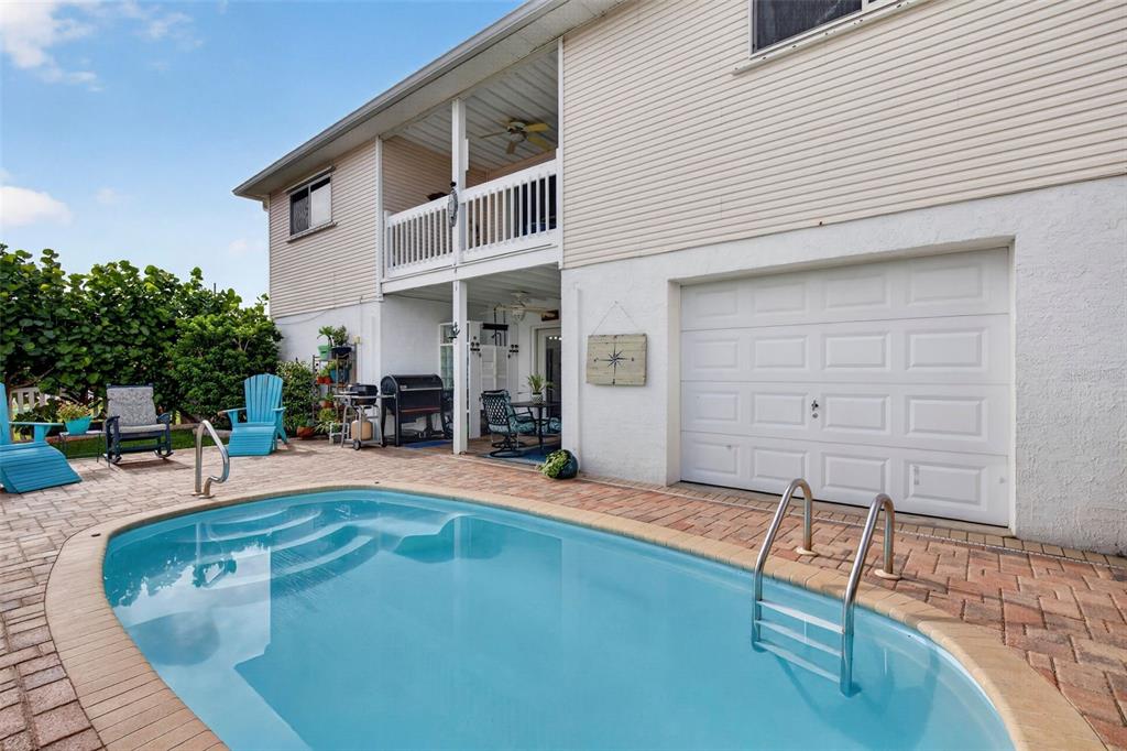 A two-story house exterior features a swimming pool, a patio, and a white garage door — 7611 MAKO DRIVE, HUDSON, FL