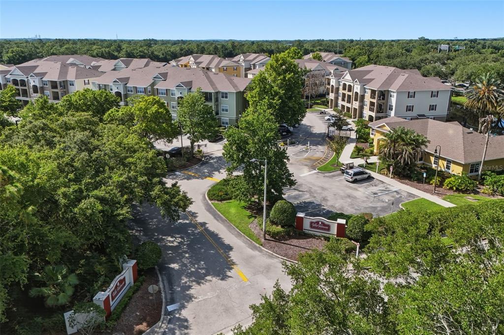 An aerial view shows the entrance and multi-story apartment buildings of a residential complex — 8201 CLAIRE ANN DRIVE UNIT 203, ORLANDO, FL