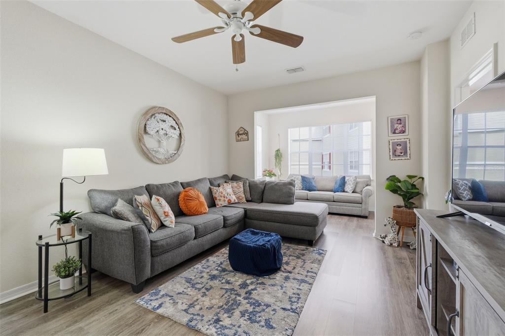 A living room features a gray sectional sofa, a blue ottoman, and a ceiling fan — 8201 CLAIRE ANN DRIVE UNIT 203, ORLANDO, FL