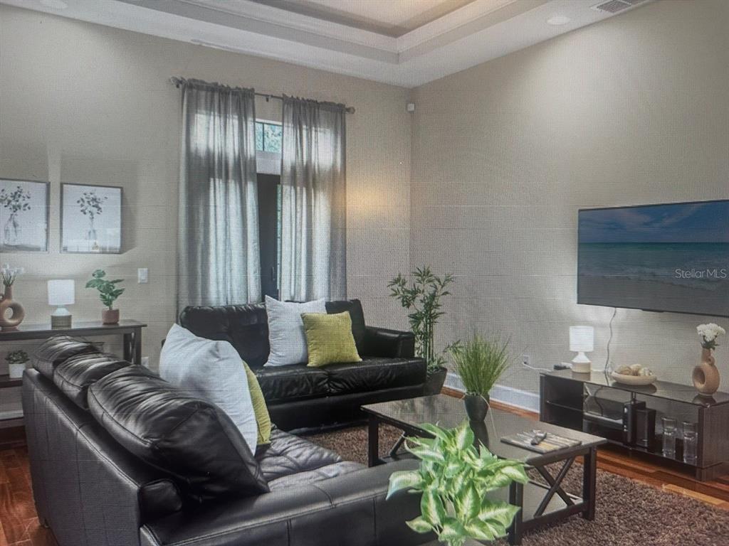 A living room features black leather sofas, a coffee table, and a wall-mounted television — 14519 DAMAI LANE, ORLANDO, FL