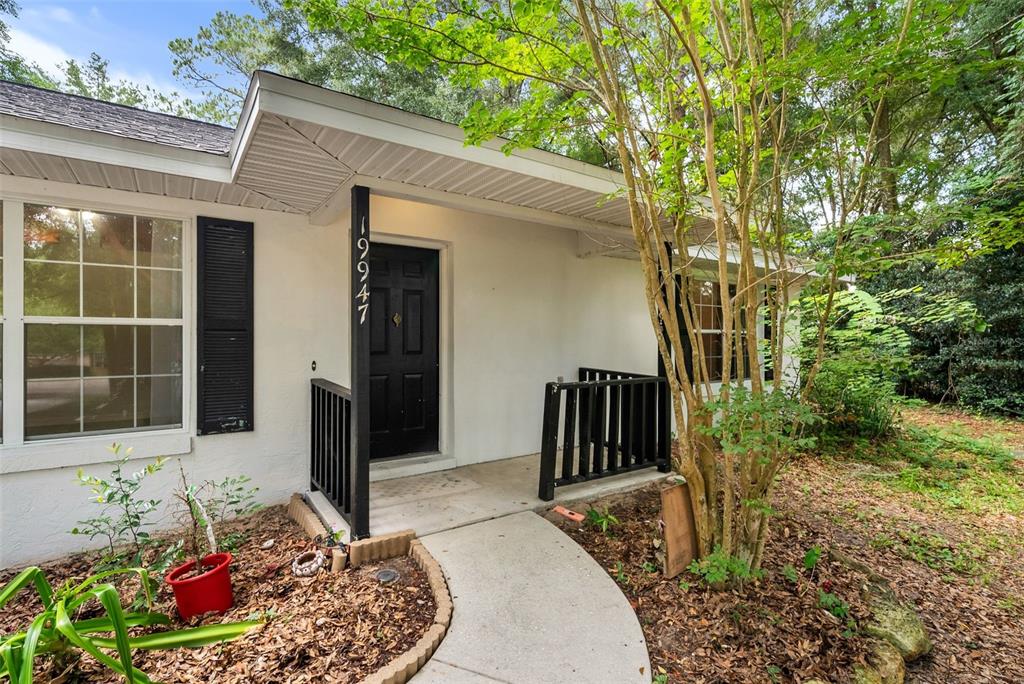 A white house exterior features a black front door, a concrete walkway, and black railings — 19947 NW 245TH TERRACE, HIGH SPRINGS, FL