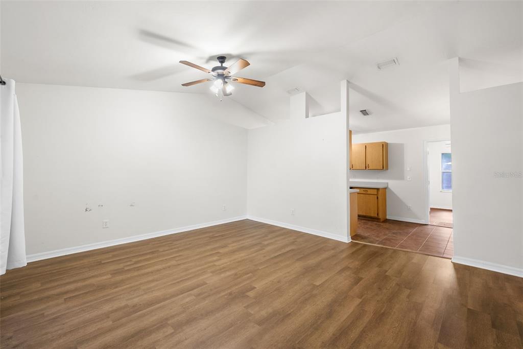 A living room with wood-look flooring, a ceiling fan, and an adjacent kitchen area — 19947 NW 245TH TERRACE, HIGH SPRINGS, FL