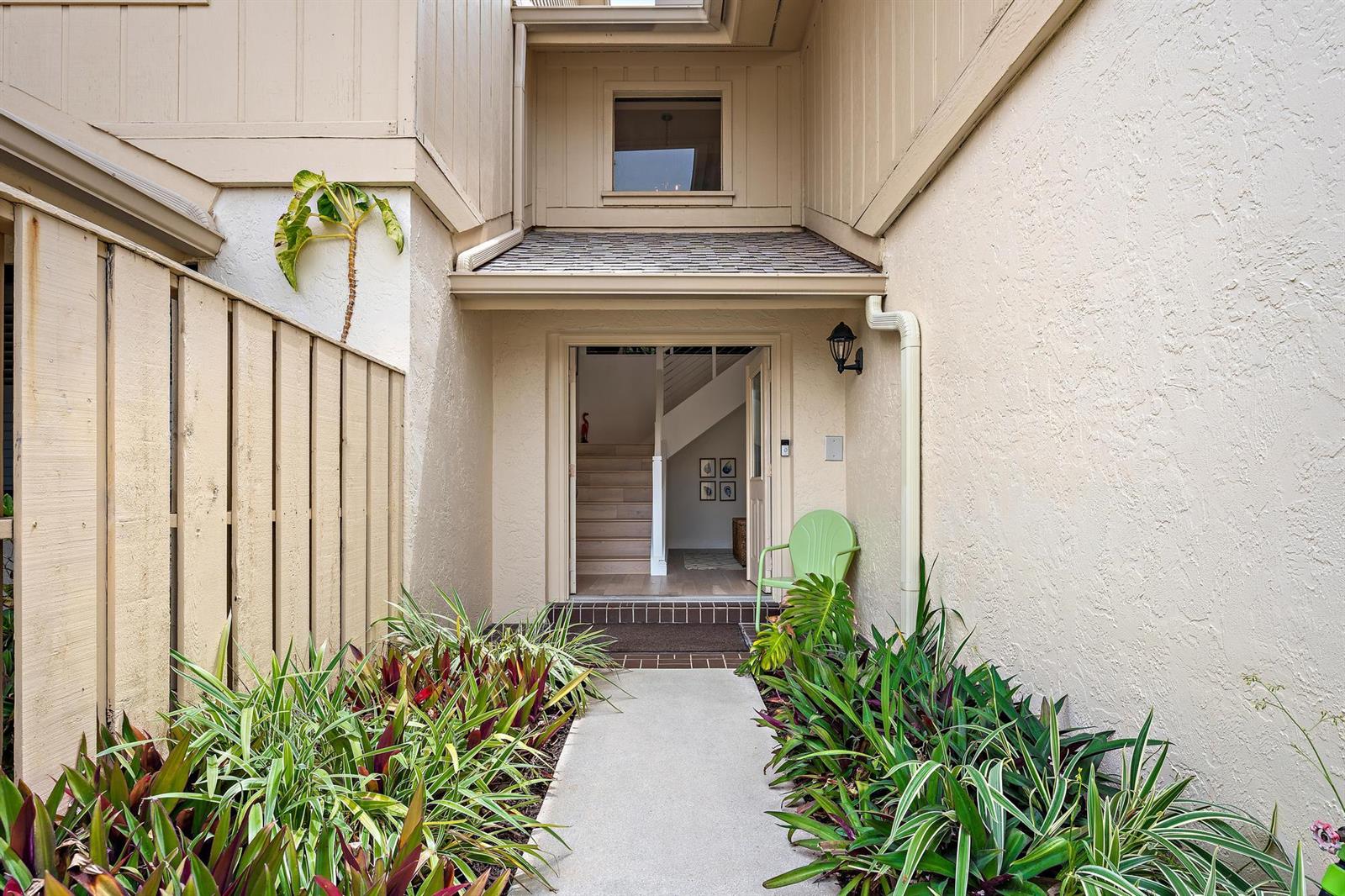 A concrete walkway leads to the front entrance of a beige home with landscaping — 17165 Waterbend Drive # 206, Jupiter FL 33477, JUPITER, FL