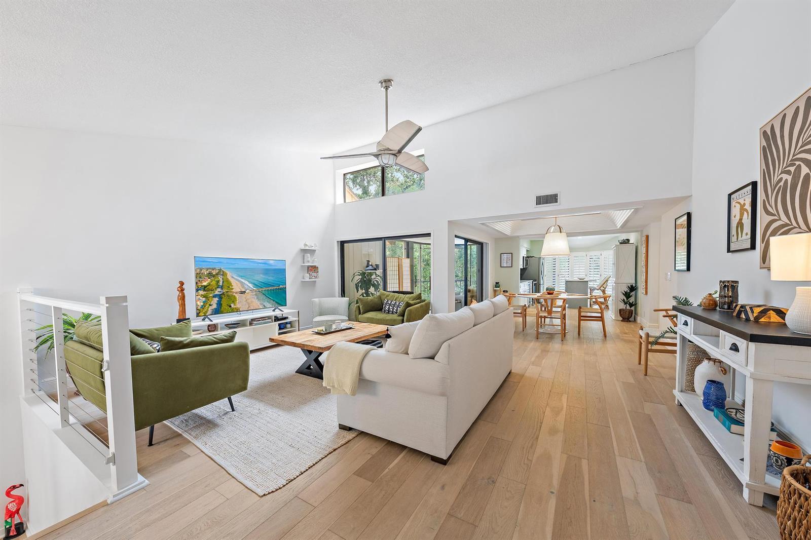 A bright living room features vaulted ceilings, light wood floors, and a mix of furniture — 17165 Waterbend Drive # 206, Jupiter FL 33477, JUPITER, FL