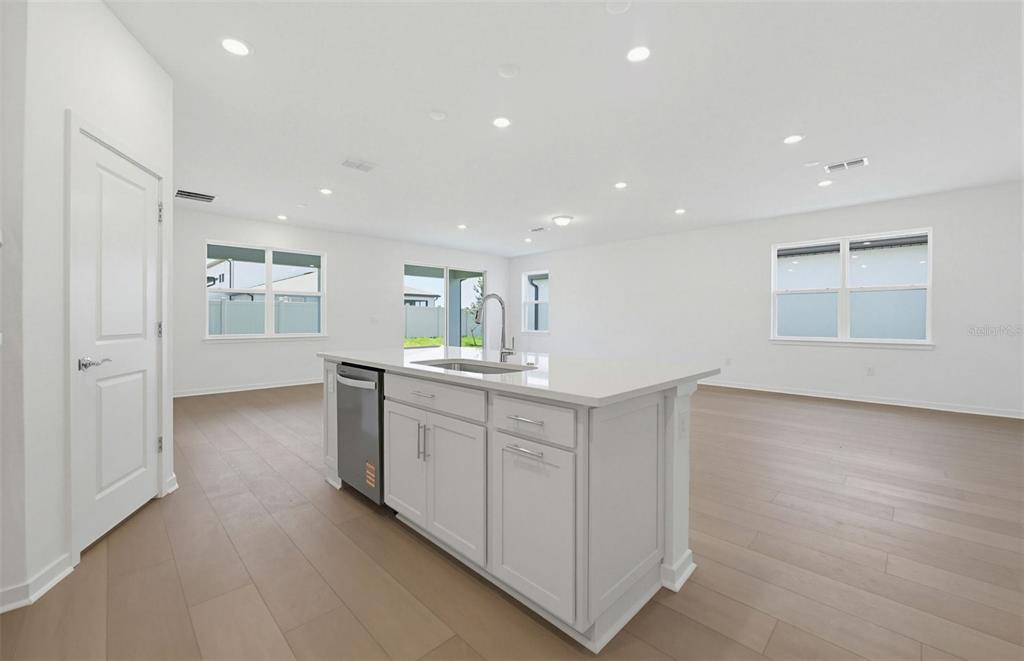 A kitchen island with a stainless steel dishwasher sits in a white, open-concept room — 33425 HERDS HALLOW WAY, WESLEY CHAPEL, FL