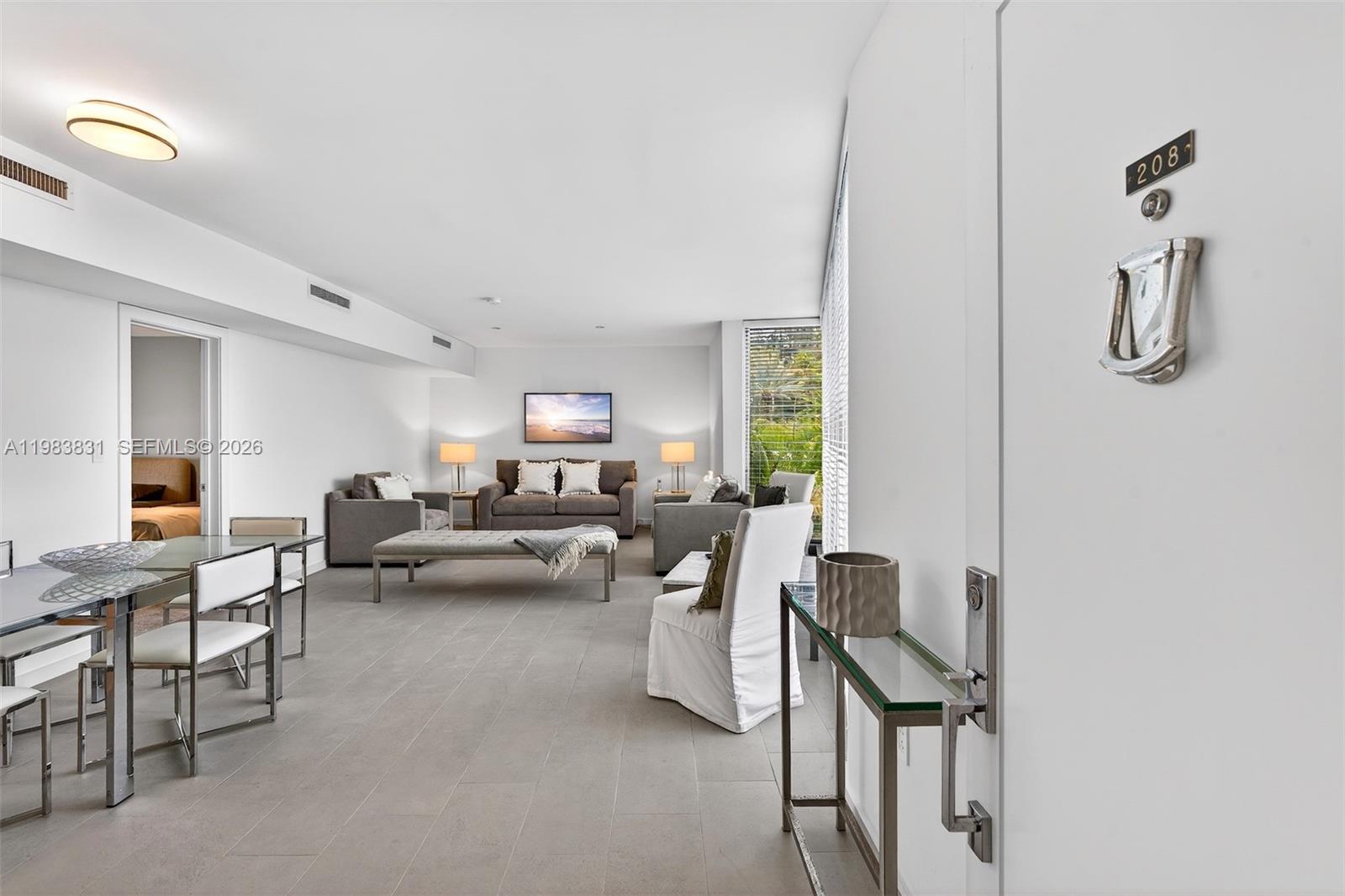 A bright, open-concept living and dining area features white walls, tile flooring, and modern furniture — 10178 Collins Ave # 208, Bal Harbour FL 33154, BAL HARBOUR, FL