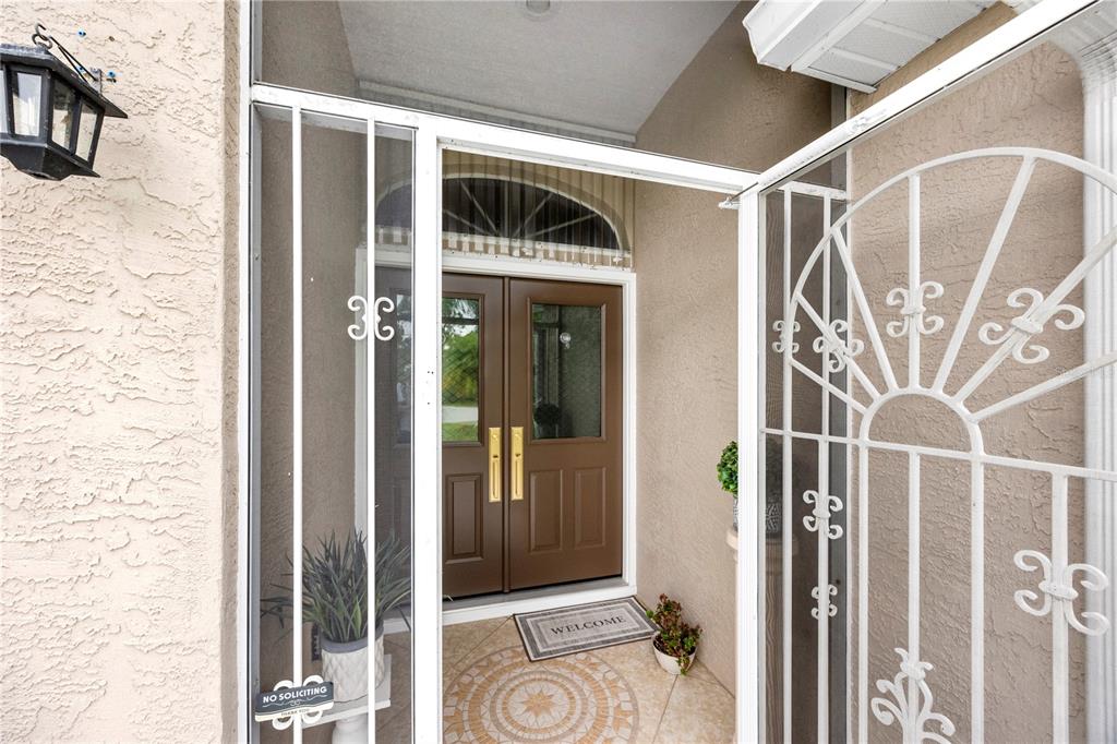 A brown double front door is visible behind a white decorative metal security gate — 4891 LIBBY COURT, NORTH PORT, FL