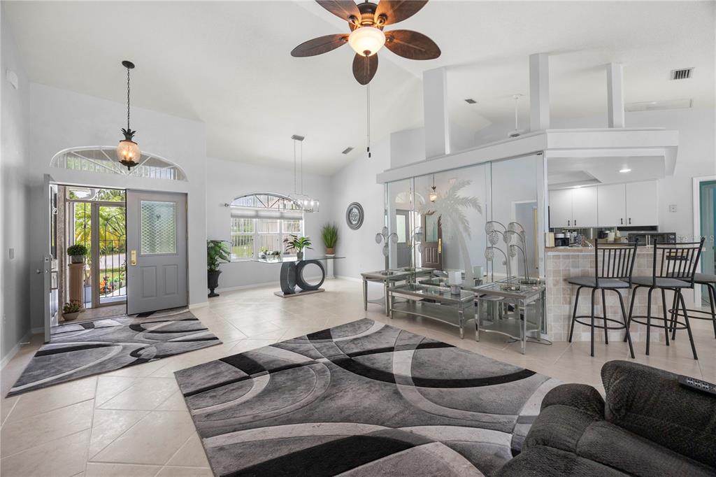 A spacious living area features tile floors, a ceiling fan, and a mirrored wall partition — 4891 LIBBY COURT, NORTH PORT, FL