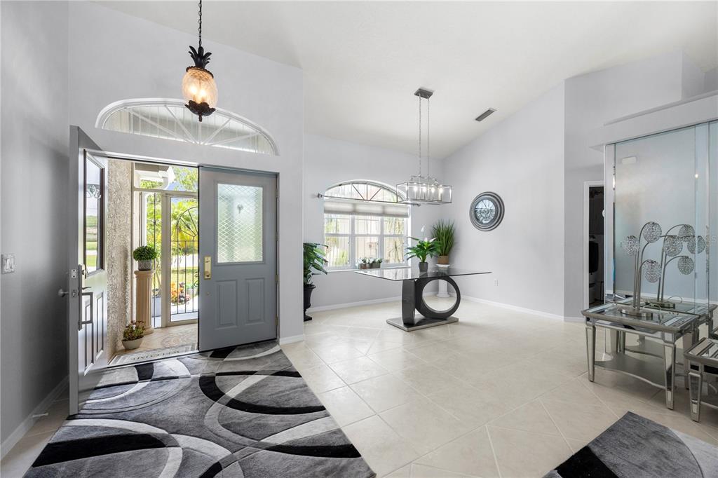 An entryway with a gray door, tiled floors, a glass dining table, and a chandelier — 4891 LIBBY COURT, NORTH PORT, FL