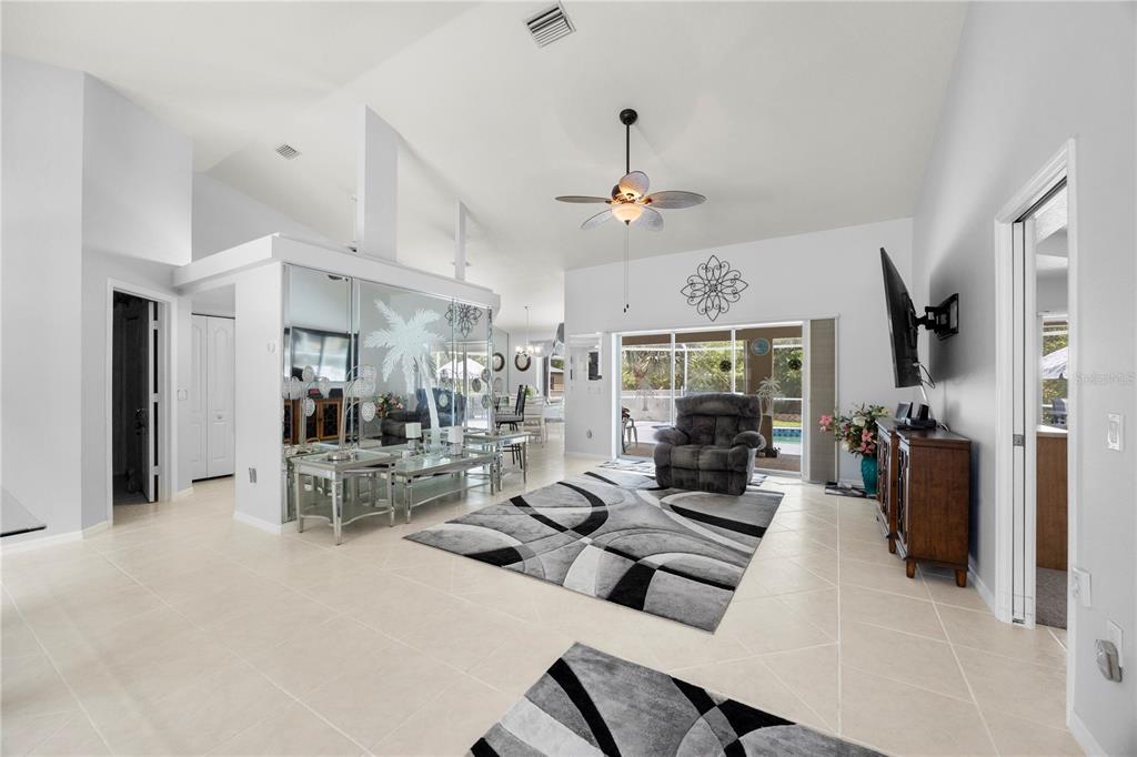 A bright living room features light tile floors, a mirrored wall, and a gray area rug — 4891 LIBBY COURT, NORTH PORT, FL