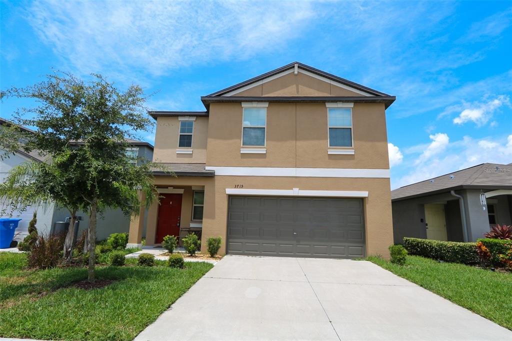 A two-story tan house with a red front door and a two-car garage — 3715 DAISY BLOOM PLACE, TAMPA, FL