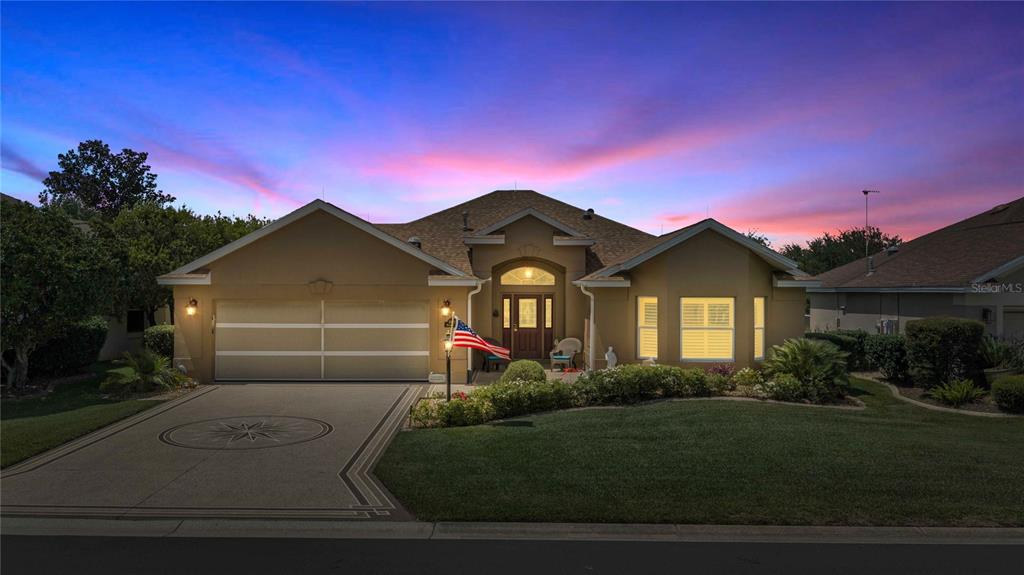 A single-story house with a tan stucco exterior, a two-car garage, and a landscaped yard — 8481 SE 168TH KITTREDGE LOOP, THE VILLAGES, FL