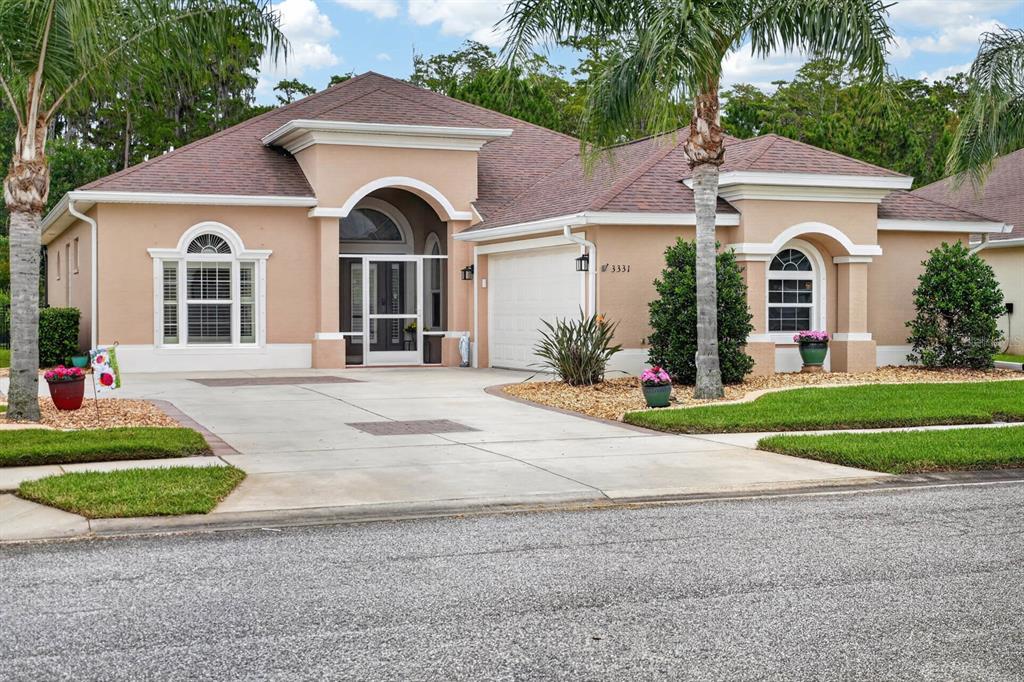 A single-story tan house with a two-car garage and a screened front entryway — 3331 BELLINO BOULEVARD, NEW SMYRNA BEACH, FL