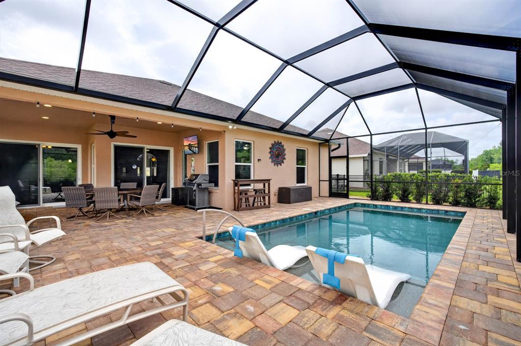 A screened-in patio features a swimming pool with lounge chairs and a paved deck — 3331 BELLINO BOULEVARD, NEW SMYRNA BEACH, FL
