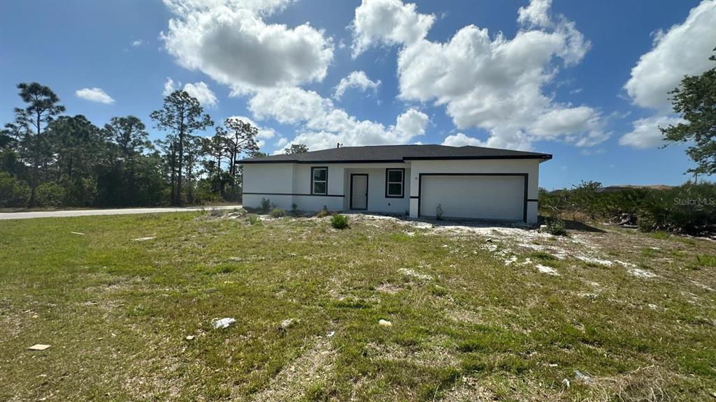 A single-story house with a white exterior, dark trim, and an attached two-car garage — 12167 FLORENCE AVENUE, PORT CHARLOTTE, FL
