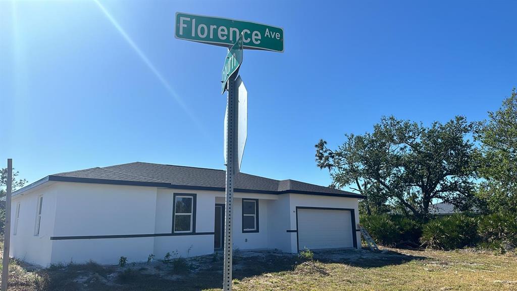 A newly constructed white single-story house with a garage stands behind a street sign — 12167 FLORENCE AVENUE, PORT CHARLOTTE, FL